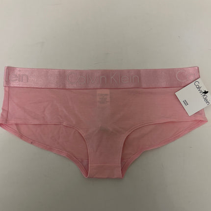 A pair of Calvin Klein pink underwear with a matching pink waistband and a white brand tag, laid flat on a light gray surface.