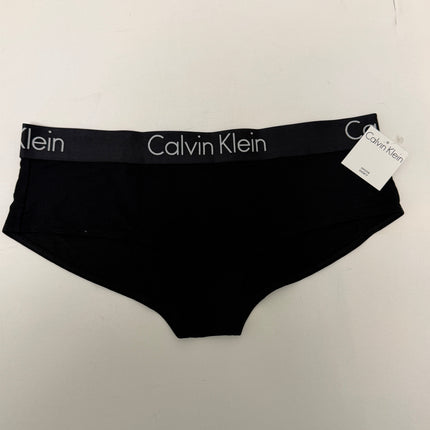 Black Calvin Klein briefs with a branded waistband and a small retail tag attached, laid flat on a light off-white surface.